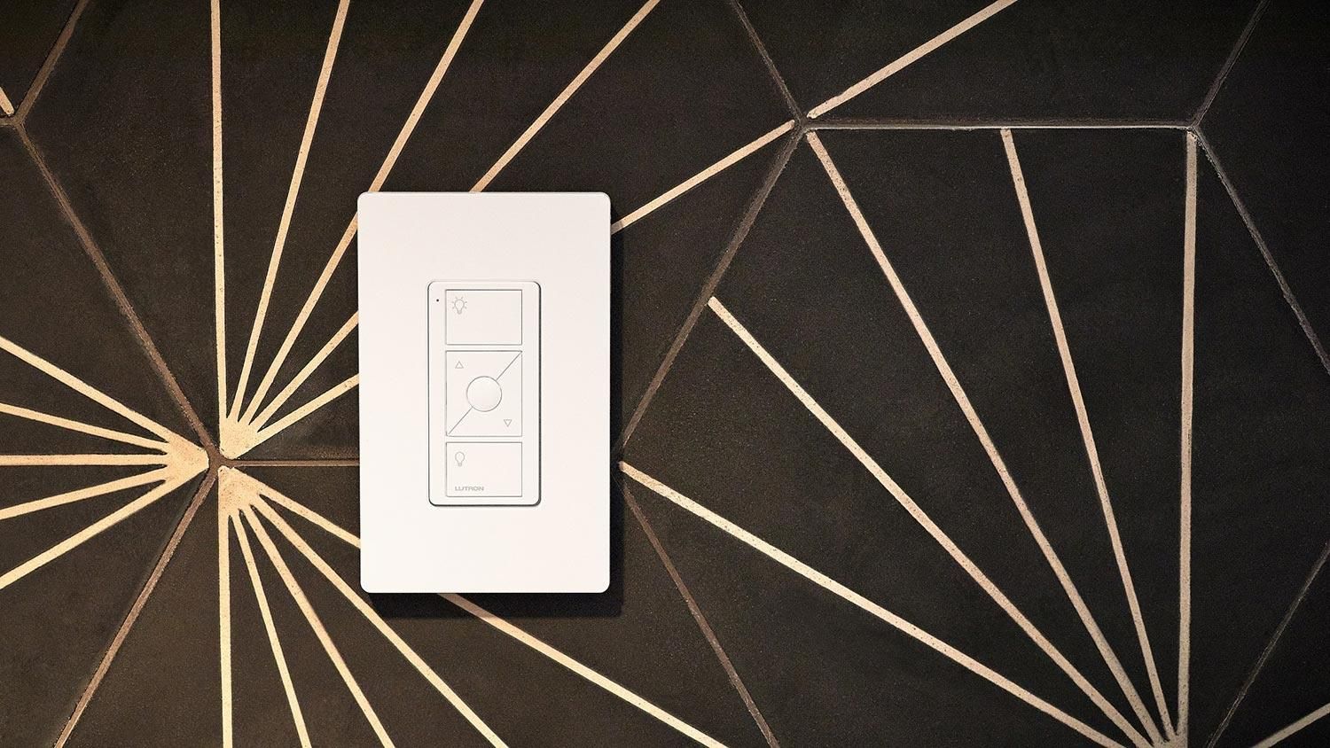 Wall-mounted Lutron smart switch on a dark geometric-patterned wall.